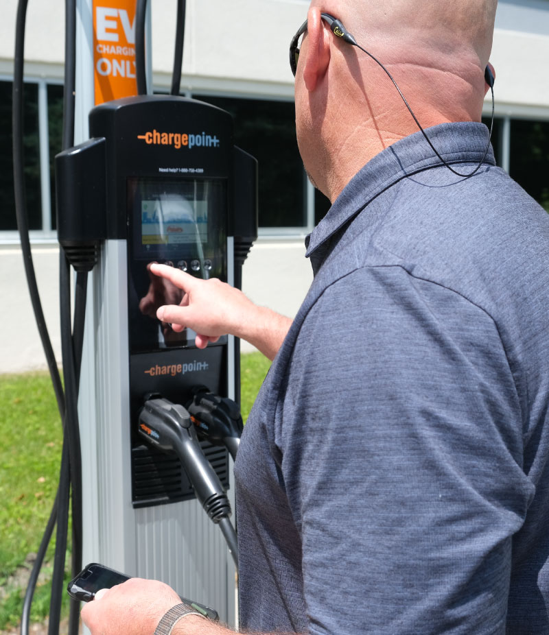 Bailiwick's Tim Bennett inspects a recently installed EV charging station.