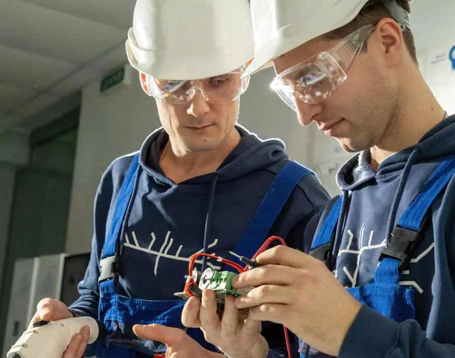 Two electricians repairing a device.