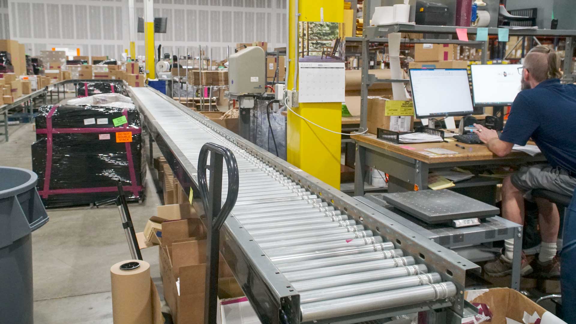 Bailiwick employee manages inventory while a conveyor belt moves items.