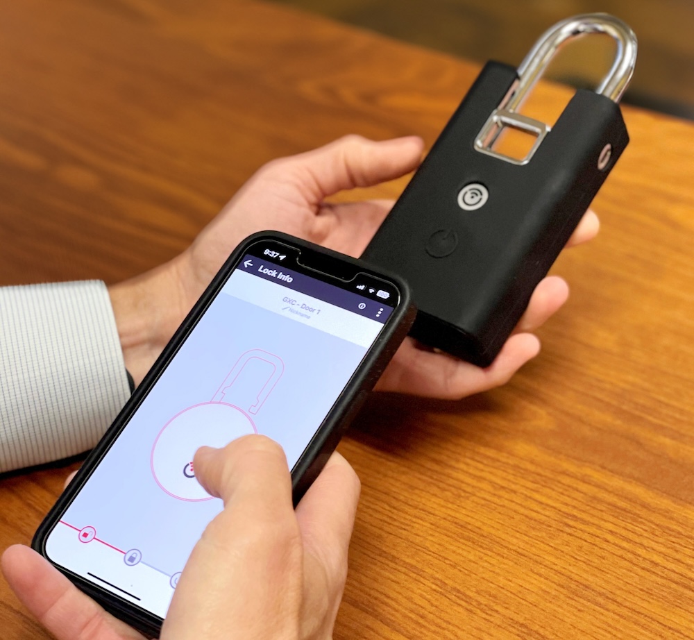 A person holding a smart phone to unlock a keyless lock.