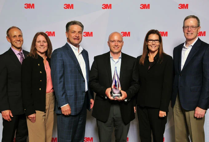 Bailiwick and 3M posing together while holding an award.