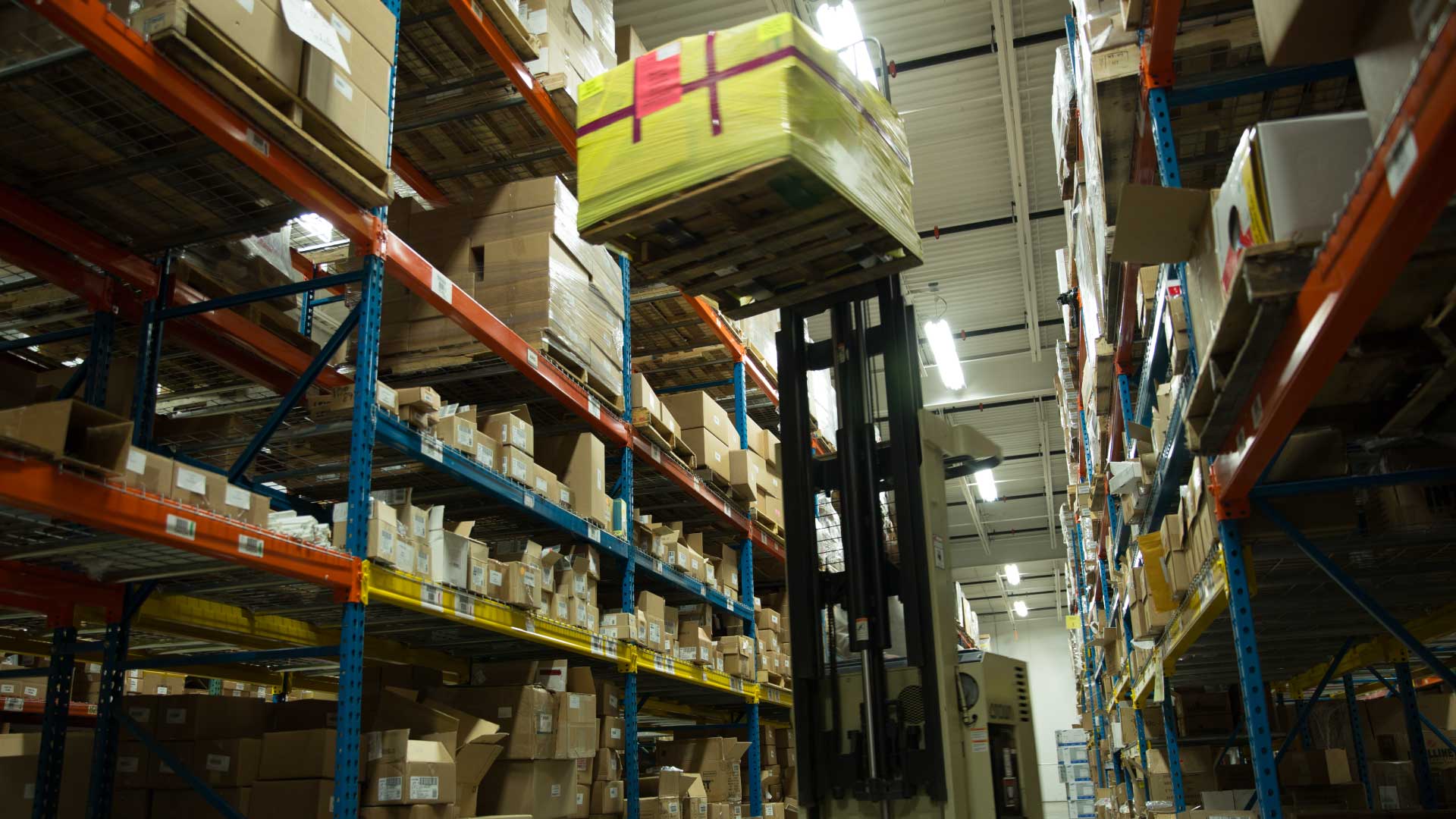 Forklift with boxes being raised into warehouse docks.