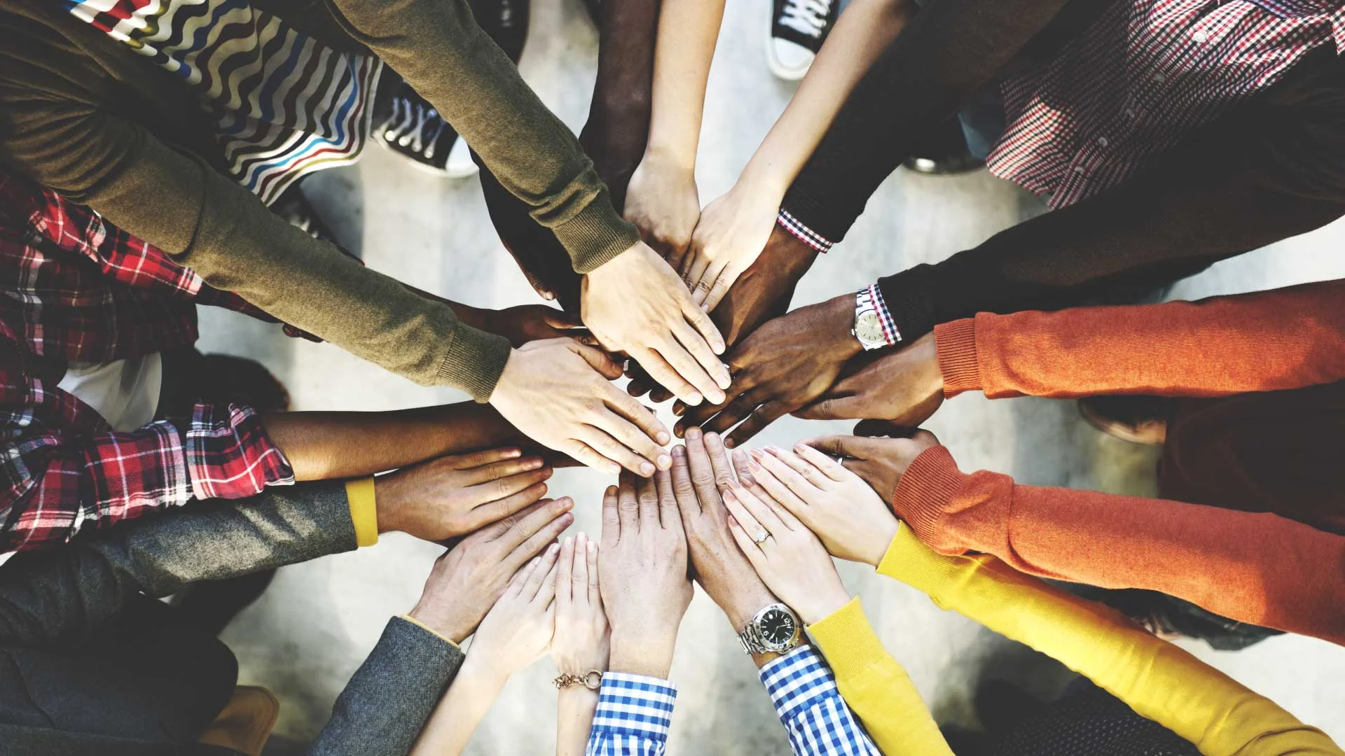 Group of diverse people holding their hands in a circle.