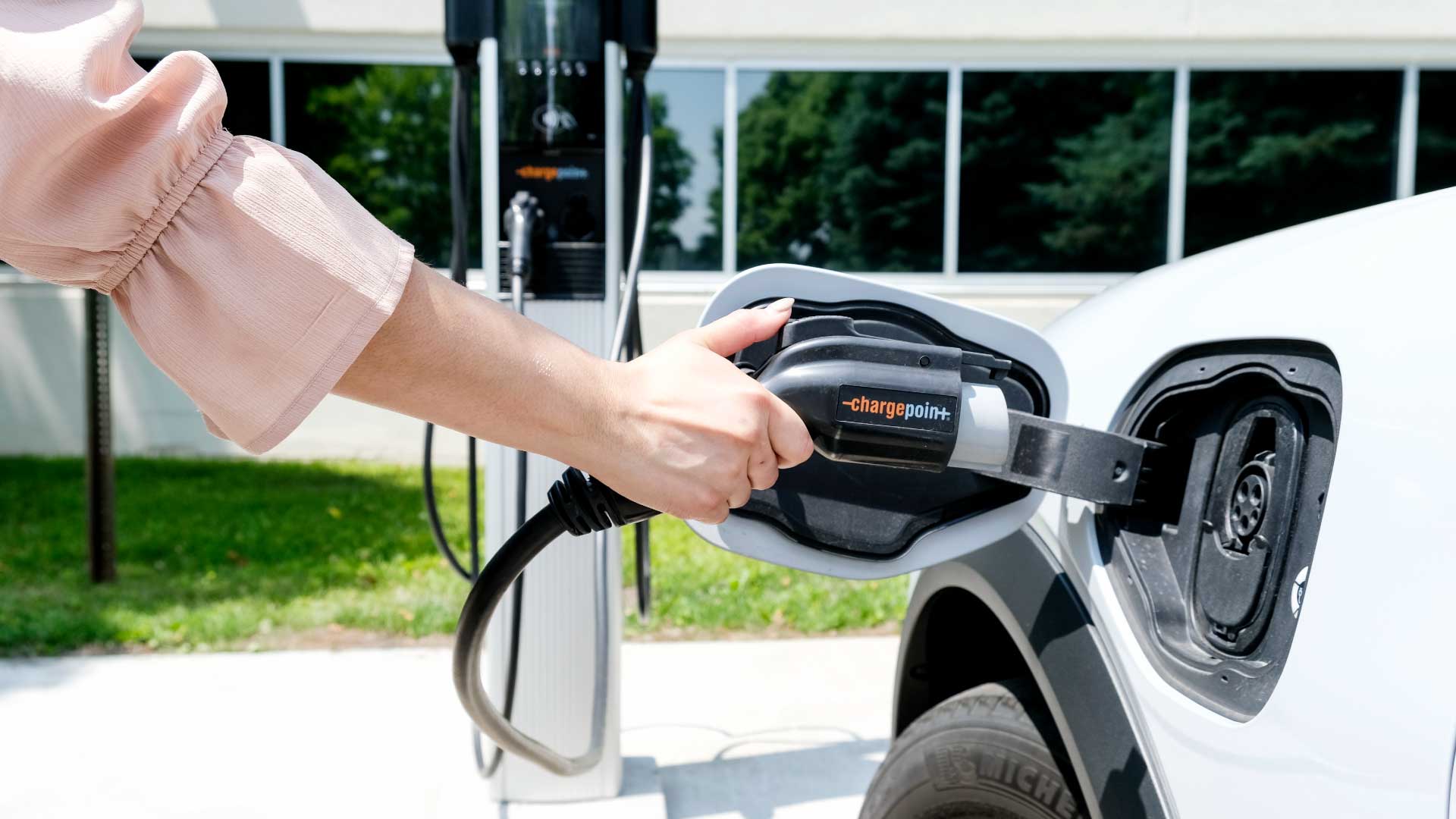 A person plugging in their EV car into a charging station.