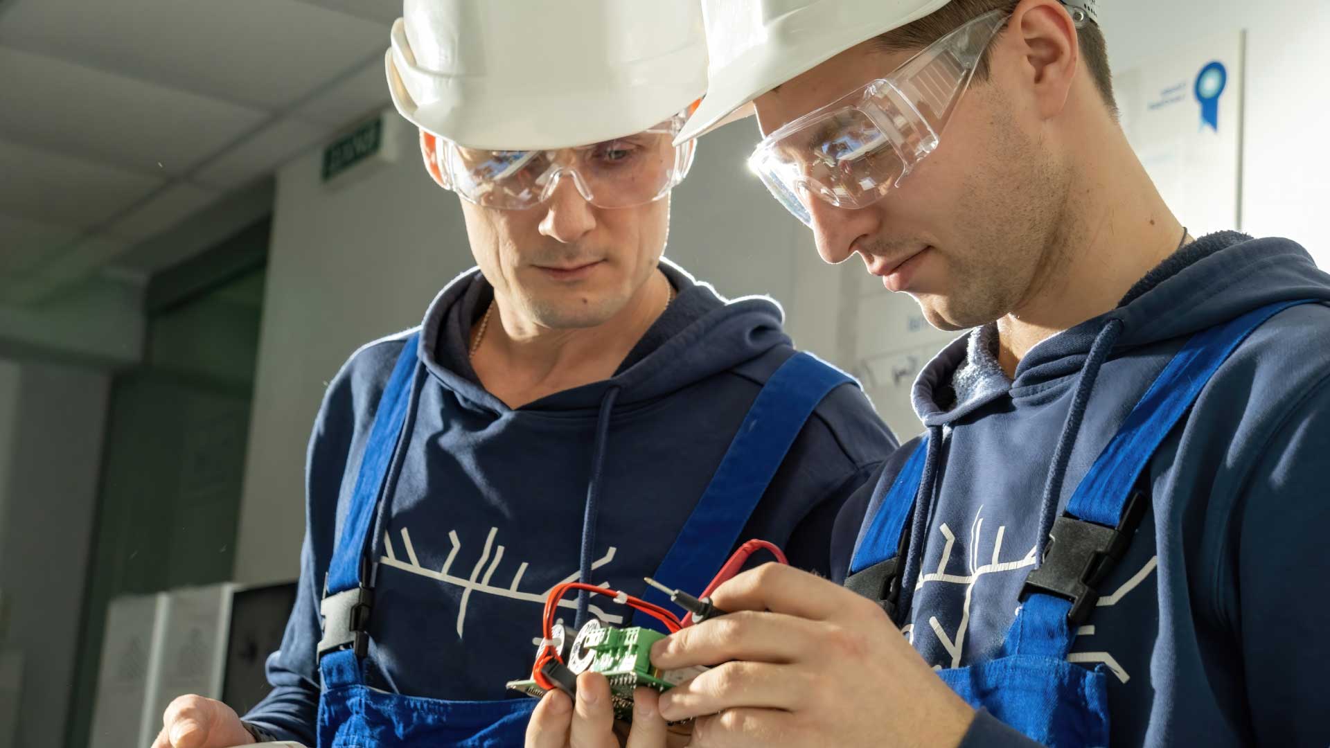 Two people in manufacturing building inspecting a device.