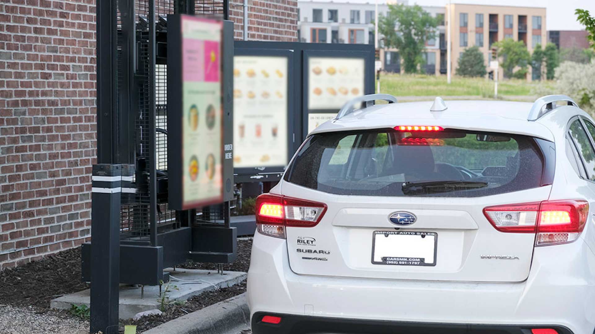 A car orders from digital menu boards at a drive-thru.