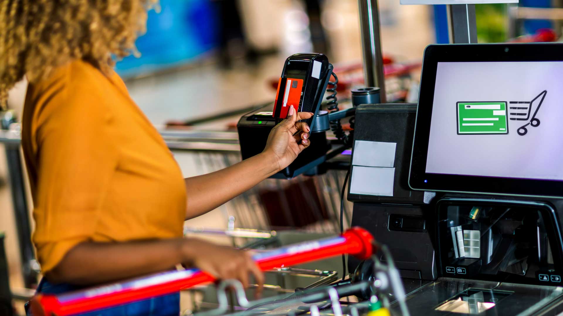 Woman using self checkout to purchase goods.