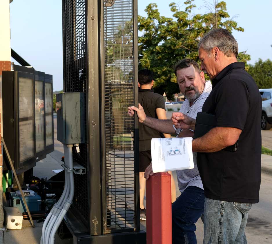 Two engineers working on an outdoor digital menu board.