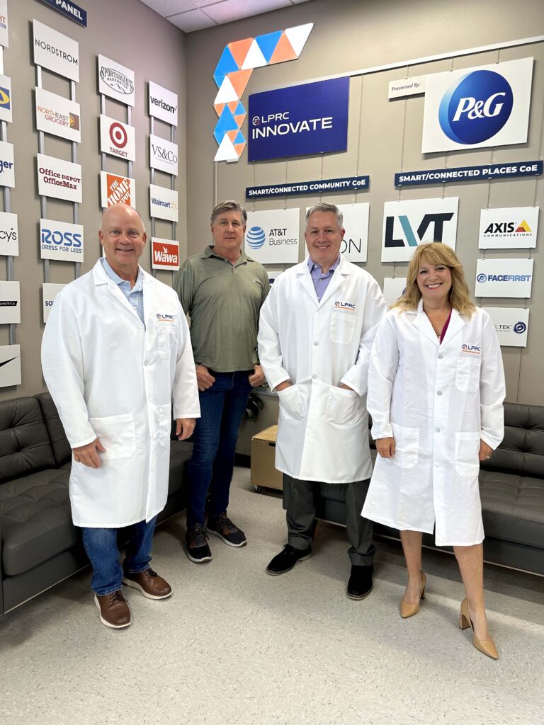 Bailiwick employees and LPRC representative standing next to many brand logos of members to the LPRC.