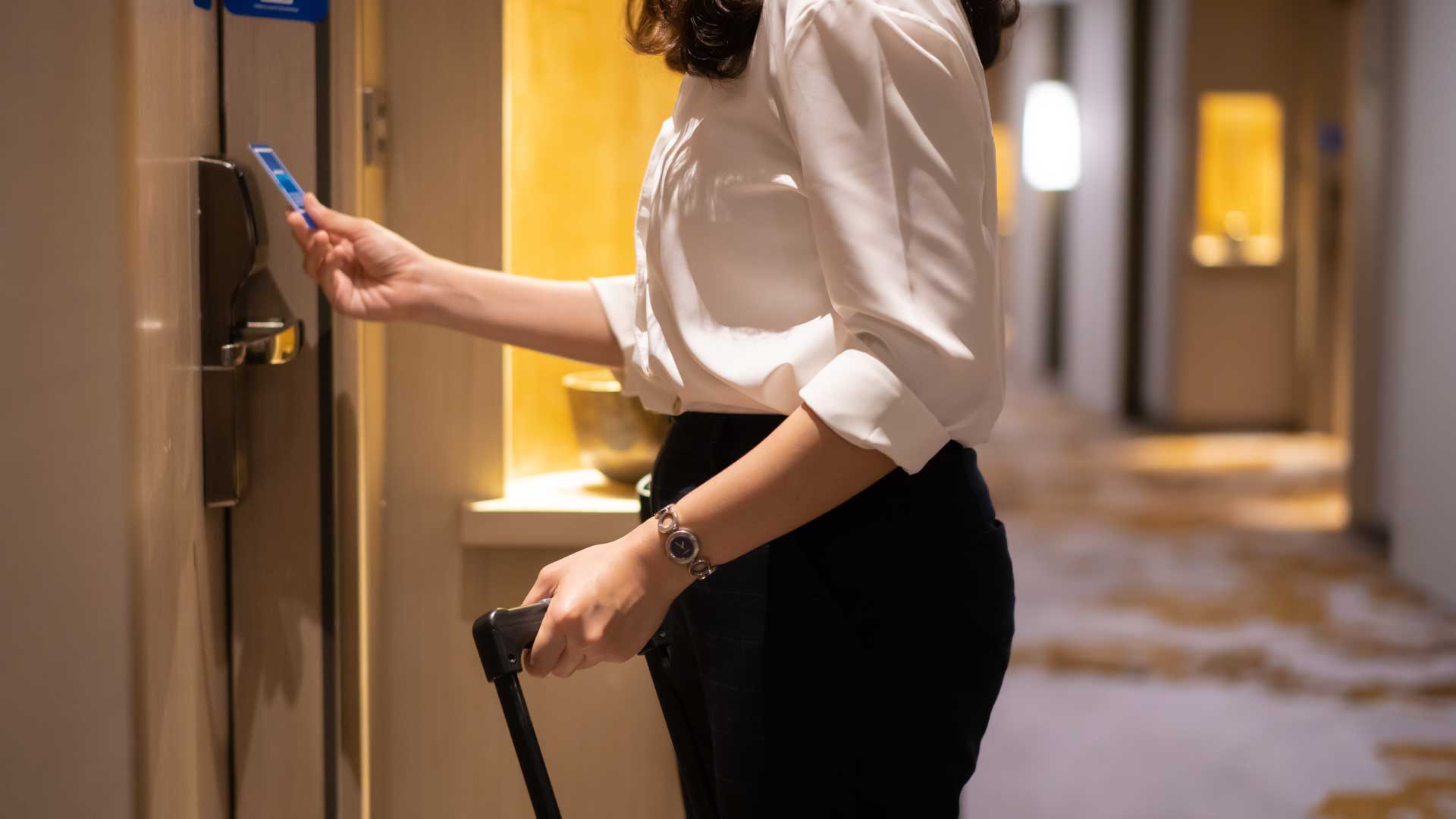 Woman using digital lock to open hotel room door.