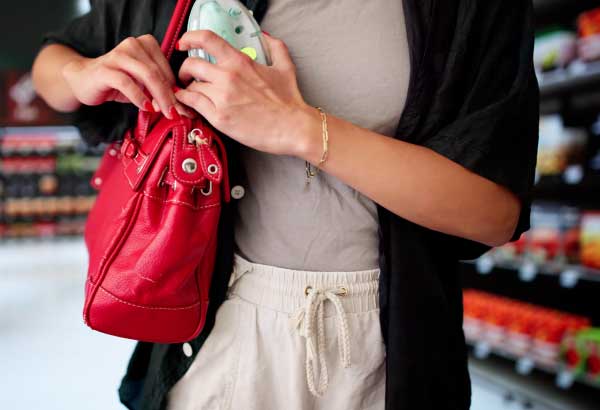 Woman putting unpaid items in her purse.